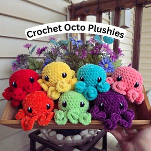 May include: A collection of colorful crochet octopus plushies in a wooden tray. The plushies are in various colors, including red, orange, yellow, green, blue, pink, and purple. The text "Crochet Octo Plushies" is displayed above the plushies.