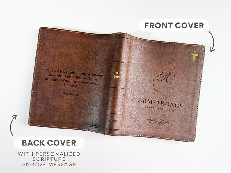 K&ouml;nnte beinhalten: Offener brauner Leder-Bibelumschlag mit goldenem Kreuz und personalisiertem Text. Der Umschlag tr&auml;gt den Namen "Armstrongs" und die Worte "Holy Bible". Die R&uuml;ckseite bietet Platz f&uuml;r personalisierte Schrift.