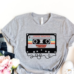 May include: A grey t-shirt with a retro cassette tape graphic. The tape has the text "Cosmic Rewind" and "Guardians of the Galaxy" printed on it.