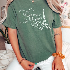 May include: A green t-shirt with a white graphic of the Eiffel Tower and the text "Take me to Paris".