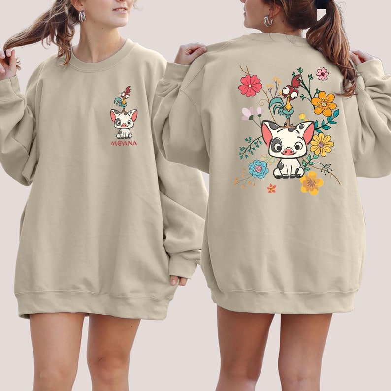 Puede incluir: Una sudadera beige con un dise&ntilde;o de cerdo y gallo de dibujos animados en la parte delantera y un cerdo de dibujos animados con flores en la parte trasera. El dise&ntilde;o de la parte delantera dice "Moana".