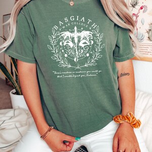 Peut inclure: Un t-shirt vert avec un motif blanc repr&eacute;sentant un dragon, une couronne et le texte "Basgiath War College". Le texte sous le graphique indique "Il n'y a nulle part o&ugrave; vous pourriez aller dans l'existence o&ugrave; je ne vous trouverais pas, Valencas."