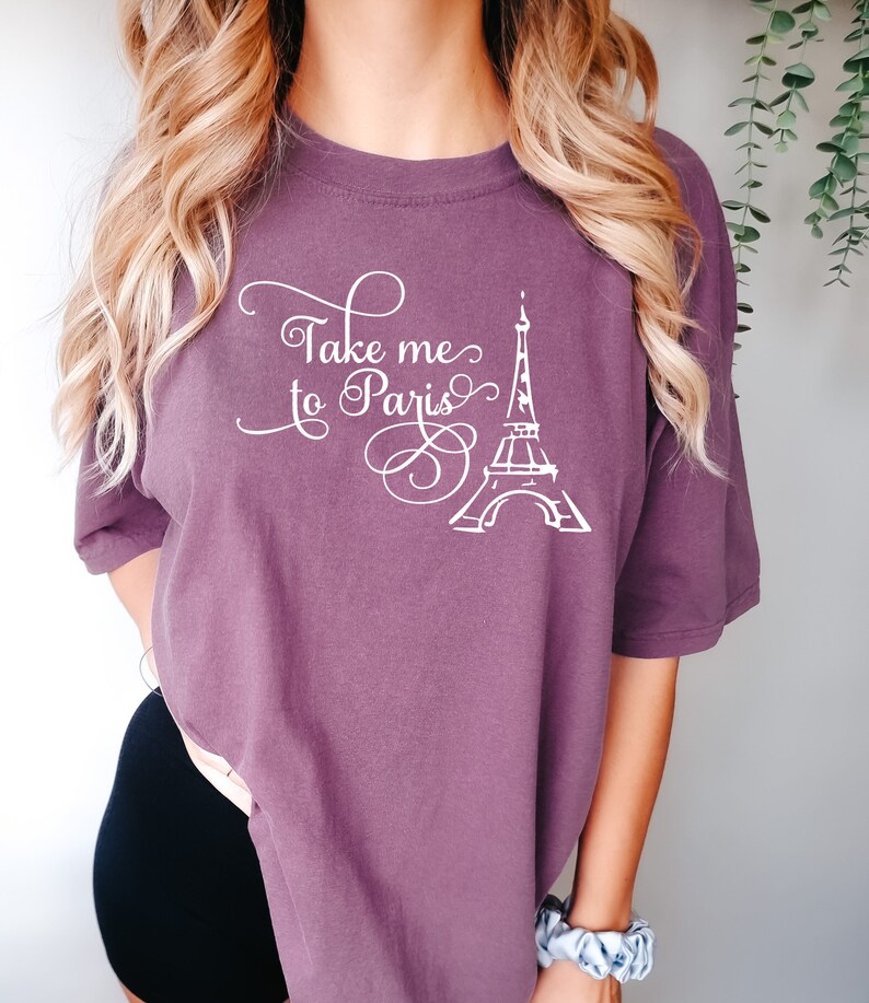 May include: A purple t-shirt with the text "Take me to Paris" and a white outline of the Eiffel Tower.