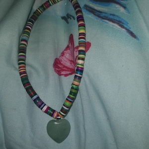 May include: A colourful beaded necklace with a green heart-shaped pendant.