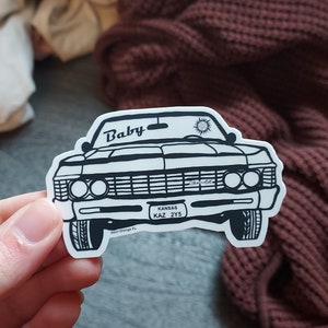 Puede incluir: Pegatina en blanco y negro de arte de línea de un coche clásico con la palabra "Baby" en el capó y la matrícula "Kansas KAZ 2YS".