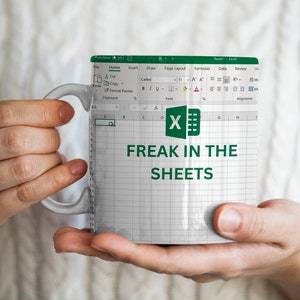 May include: A white ceramic mug with a green and white design featuring the Microsoft Excel logo and the text "Freak in the Sheets".