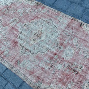 May include: A vintage rug with a faded pink and white color scheme. The rug has a central medallion design with intricate floral patterns.