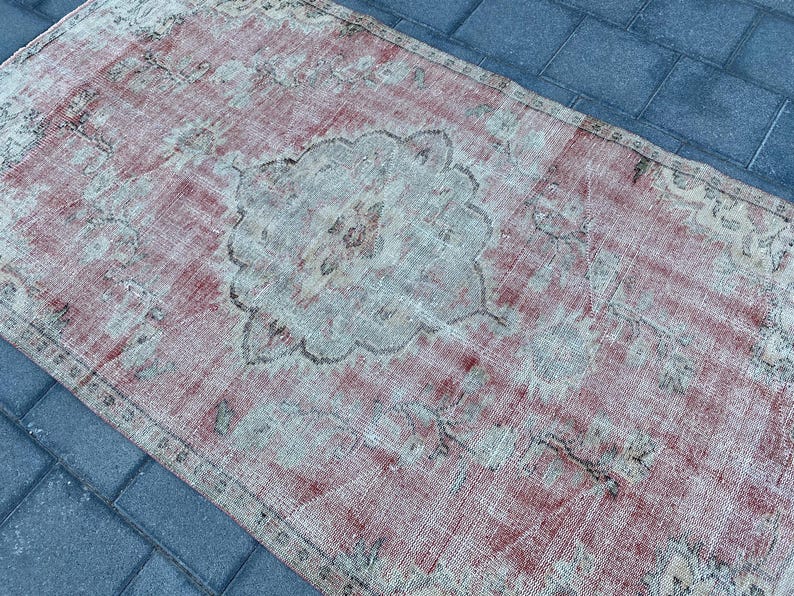 May include: A vintage rug with a faded pink and white color scheme. The rug has a central medallion design with intricate floral patterns.