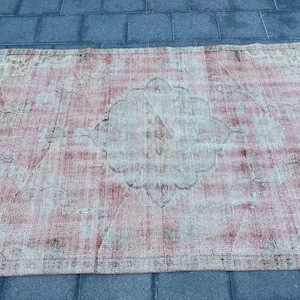 May include: A vintage rug with a faded pink and cream color scheme. The rug has a central medallion design with intricate floral patterns.
