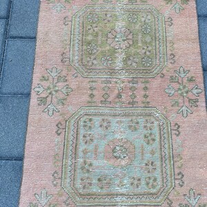 May include: A pink and green patterned rug with a floral design. The rug has a distressed look and is made of a soft, woven material.