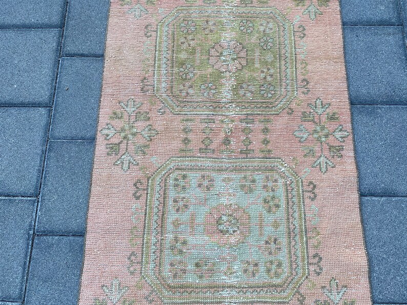 May include: A pink and green patterned rug with a floral design. The rug has a distressed look and is made of a soft, woven material.