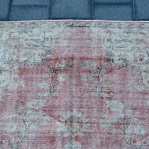 May include: A vintage rug with a faded pink background and a floral pattern in shades of gray and white.