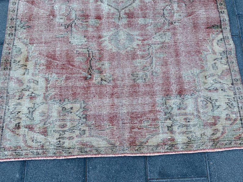 May include: A vintage rug with a faded pink and cream color scheme. The rug has a traditional Persian design with intricate floral patterns.