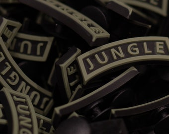 Peut inclure: Gros plan sur un tas de boucles en plastique noires et vertes avec le mot "JUNGLE" en relief.