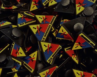 Peut inclure: Un tas de breloques de chaussures en caoutchouc triangulaires, jaunes, rouges et bleues avec le texte "Old Ironsides" et "1" dessus.