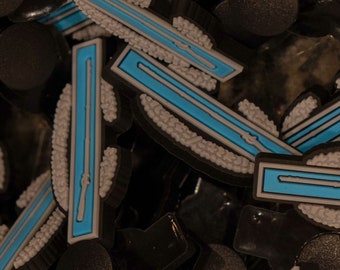 Peut inclure: Gros plan sur plusieurs breloques en plastique noir et bleu en forme d'insigne de grade militaire. Les breloques ont une bordure blanche et une bande bleue au centre.