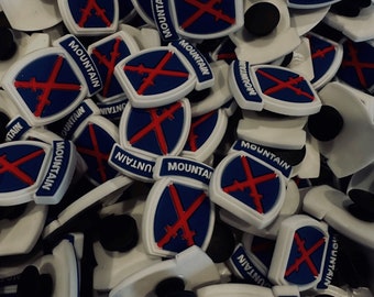 Peut inclure: Gros plan sur un tas de boutons en plastique blanc et bleu avec le mot "MOUNTAIN" et un motif de croix rouge.
