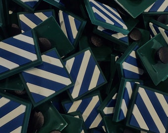 Peut inclure: Un ensemble de supports de téléphone carrés verts. Chaque support présente un motif de rayures diagonales bleues et blanches. Les supports ont un bouton noir circulaire à l'arrière. Fond blanc.