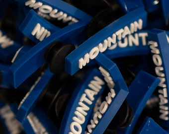 Peut inclure: Gros plan sur des bouchons d'oreilles en plastique bleu avec le mot "Mountain" imprimé en blanc sur chaque bouchon.