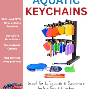 May include: A black metal display stand holding multiple colorful 3D printed PETG aquatic keychains in various shapes. Some keychains feature text including LIFEGUARD and KICK IS KICK, NOT PULL. The display includes blue, orange, yellow, green, and purple items.