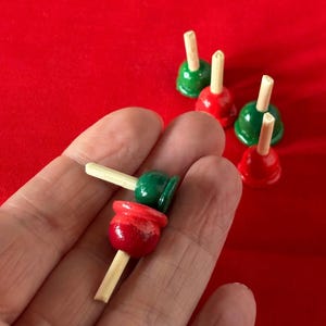 以下が含まれることがあります： 赤と緑に塗られたミニチュアの木製おもちゃの栓抜き5個セット。栓抜きは積み重ねられており、上の栓抜きは緑、下の栓抜きは赤です。