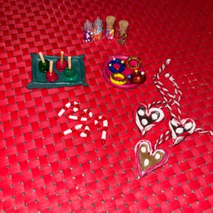 May include: A collection of miniature candy and sweets made from polymer clay. The set includes candy canes, heart-shaped cookies, donuts, and candy apples. There are also three small jars filled with colorful sprinkles.