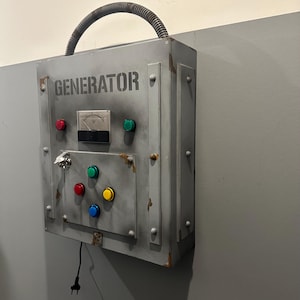 May include: A gray metal box with the word "GENERATOR" printed on it. The box has a variety of buttons and a keyhole. There is a black electrical cord plugged into the box.