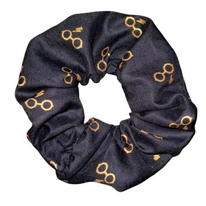 May include: Black scrunchie with a gold pattern of glasses and lightning bolts.