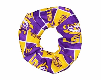 May include: Purple and gold scrunchie with a repeating pattern of the LSU logo and tiger mascot.