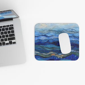 May include: Blue and white abstract mouse pad with a layered design resembling waves or mountains. The mouse pad is made of a smooth, durable material and is perfect for use with a computer mouse.