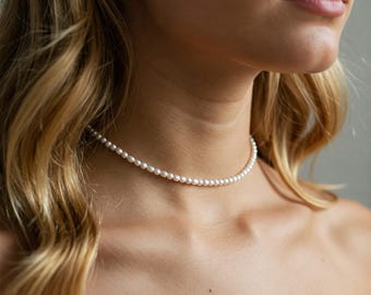 May include: A delicate pearl choker necklace with small, white pearls. The necklace is simple and elegant, perfect for everyday wear.