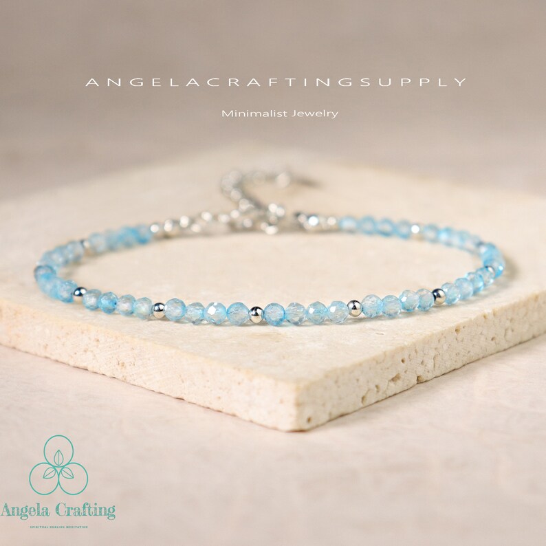 May include: A delicate bracelet featuring small, faceted light blue beads interspersed with polished silver-tone metal spheres. The piece includes a silver-tone metal chain extension and clasp. Text reads ANGELACRAFTINGSUPPLY and Minimalist Jewelry.
