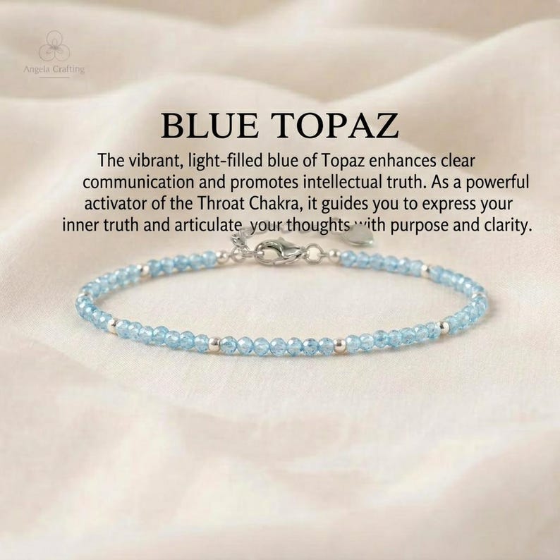 May include: A delicate bracelet featuring small, faceted light blue topaz beads interspersed with tiny silver-toned metal spheres. The piece includes a silver-toned lobster claw clasp and a small heart-shaped charm. Text reads: BLUE TOPAZ.