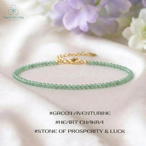 May include: A delicate bracelet featuring small, round, light green aventurine beads strung together. The piece includes a gold-toned metal chain extender and a lobster claw clasp. Text below reads: #GREEN AVENTURINE #HEART CHAKRA #STONE OF PROSPERITY & LUCK.