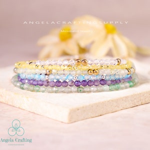 May include: A stack of five beaded bracelets featuring faceted clear, yellow, light blue, purple, and green beads interspersed with small metallic gold and silver spheres. The text ANGELACRAFTINGSUPPLY and Angela Crafting are visible.