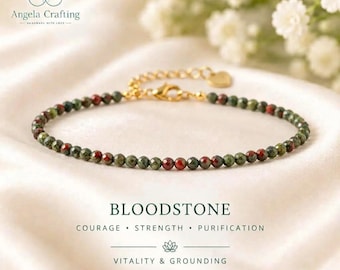 May include: A delicate bracelet featuring small, faceted bloodstone beads in shades of dark green and deep red, accented with a gold-toned metal chain, a lobster clasp, and a small heart-shaped charm. The text reads BLOODSTONE, COURAGE, STRENGTH, PURIFICATION, VITALITY & GROUNDING.