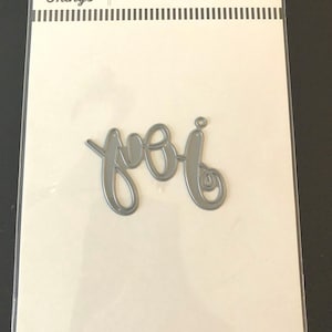 May include: A silver metal die cut with the word "you" in a cursive font. The die cut is packaged in a white card with the text "My Favorite Things" and "Die-namics" printed on it.
