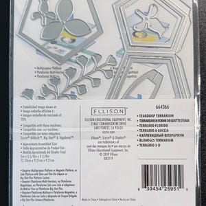 Puede incluir: Un juego de troqueles de metal Sizzix Thinlits para un terrario en forma de gota, modelo 664366. El paquete incluye troqueles plateados con formas de marcos geom&eacute;tricos y flores. La etiqueta muestra el nombre del producto y datos.