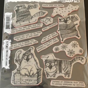 May include: A clear plastic package containing rubber stamps with whimsical cat illustrations in black and white. The stamps have a Christmas theme, with phrases like "Meowy Christmas" and "Jingle your own bells."