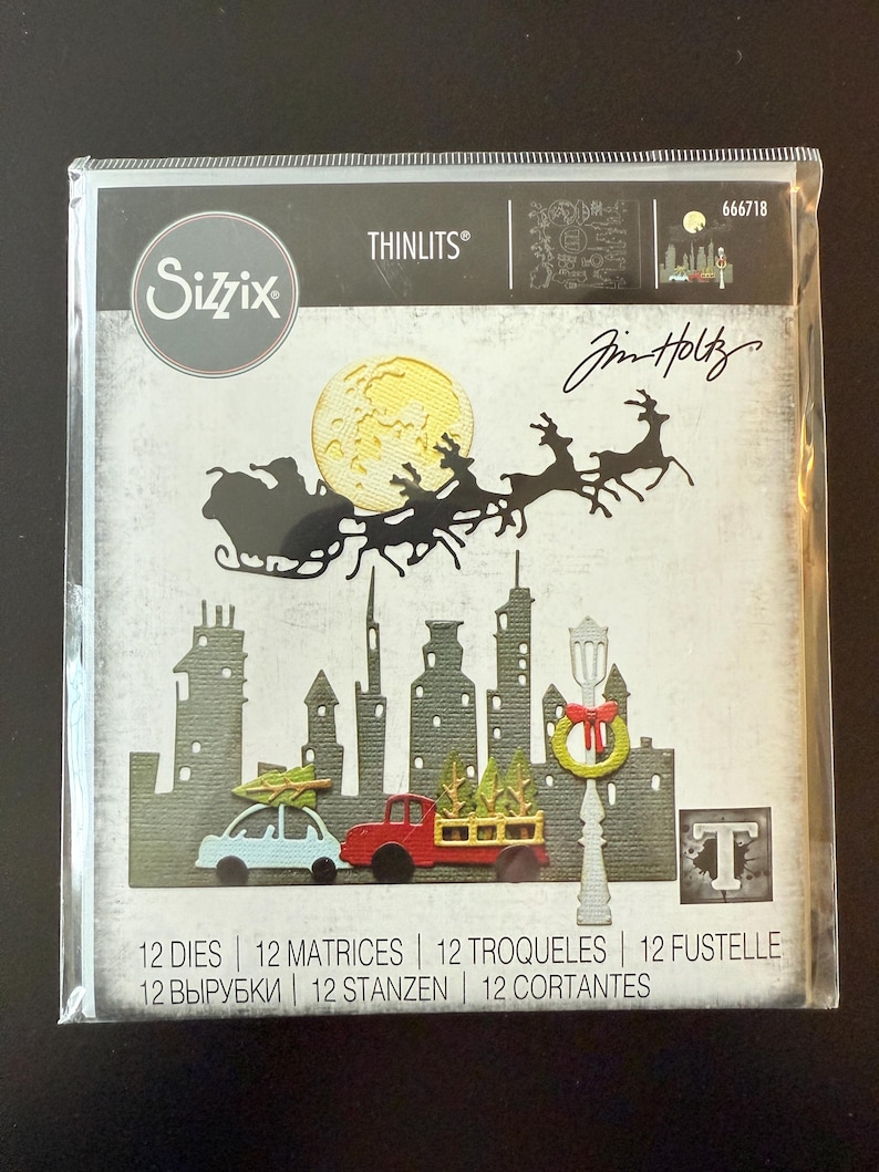 Op de afbeelding: Sizzix Thinlits stansvormenset met een kerstthema. Het ontwerp bevat een silhouet van de slee van de kerstman met rendieren, een stadsgezicht en feestelijke voertuigen. Het pakket bevat 12 stansvormen, 12 matrices en 12 andere componenten.