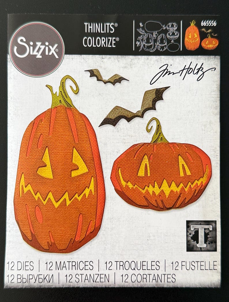 May include: A Sizzix Thinlits Colorize die set by Tim Holtz, model 665556, featuring 12 metal cutting dies. The packaging displays die-cut images of two orange jack-o'-lantern pumpkins with green stems and two brown bats on a white background.