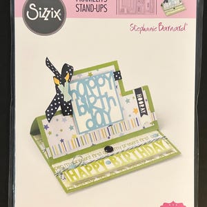 May include: Sizzix Framelits Stand-Ups die set for cardmaking. The packaging shows a completed birthday card with the words "Happy Birthday" and "Hooray". The set includes 28 dies. Designed by Stephanie Barnard.