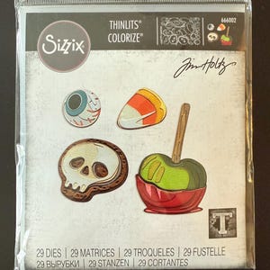 May include: A package of Sizzix Thinlits Colorize dies featuring Halloween-themed shapes. The designs include a skull, eyeball, candy corn, and a caramel apple. The package also includes the text "29 DIES | 29 MATRICES | 29 TROQUELES | 29 FUSTELLE".