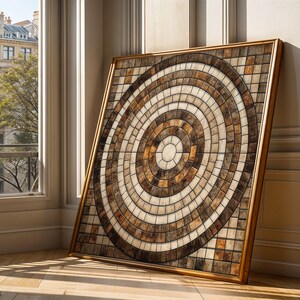 May include: A large, square framed artwork with a mosaic design of concentric circles in brown, beige, and cream tones. The artwork is leaning against a wall near a window. The room is lit by sunlight.