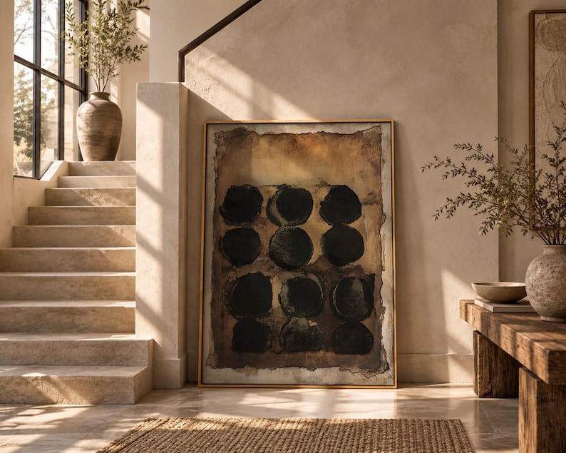 May include: A rectangular wall art piece in a thin gold frame featuring a grid of nine solid black circles set against a textured, layered background of deep brown, tan, and cream tones, creating a high-contrast abstract composition.