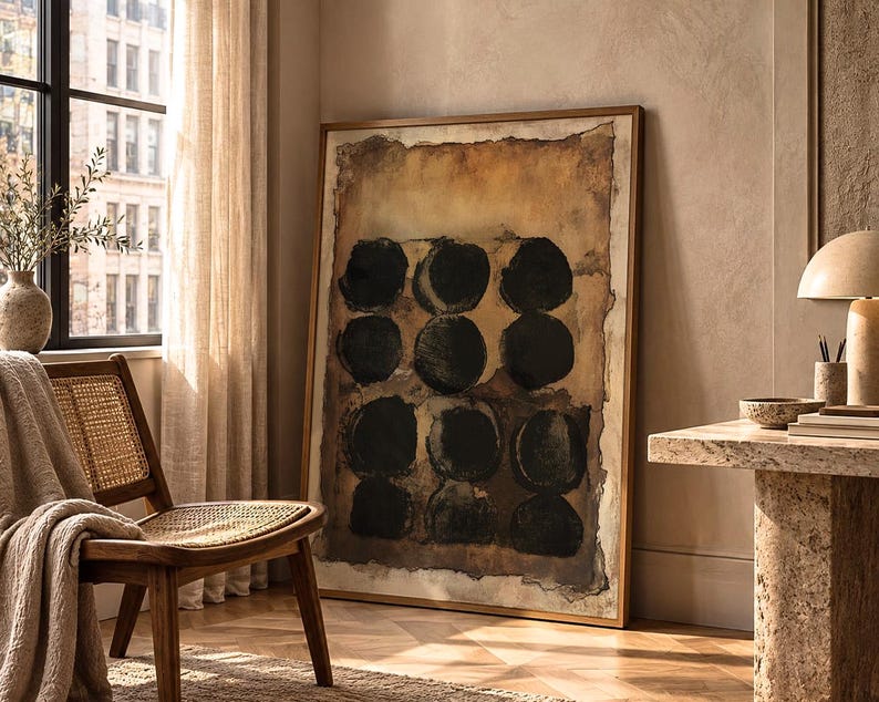May include: A large rectangular framed wall art piece featuring a grid of twelve solid black circles painted on a textured, distressed background of earthy brown, tan, and cream tones, enclosed within a thin, simple metallic frame.