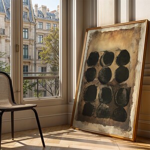 May include: A large rectangular framed painting featuring a grid of nine dark black circles arranged in three rows of three. The background of the artwork consists of layered shades of brown, tan, and beige with a textured, weathered appearance.