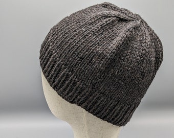 May include: A dark gray knit beanie hat displayed on a mannequin head. The hat has a ribbed design at the brim and a textured appearance. The hat is made of a soft, warm material, perfect for cold weather.