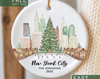 May include: A round white ceramic ornament featuring a watercolor illustration of a New York City skyline with a large Christmas tree, an ice skating rink, and market stalls. The text reads New York City, THE JOHNSONS, and 2025.