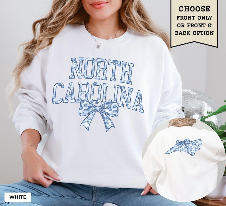 A woman wearing a white sweatshirt with the text "NORTH CAROLINA" printed on it, along with a blue bow design.